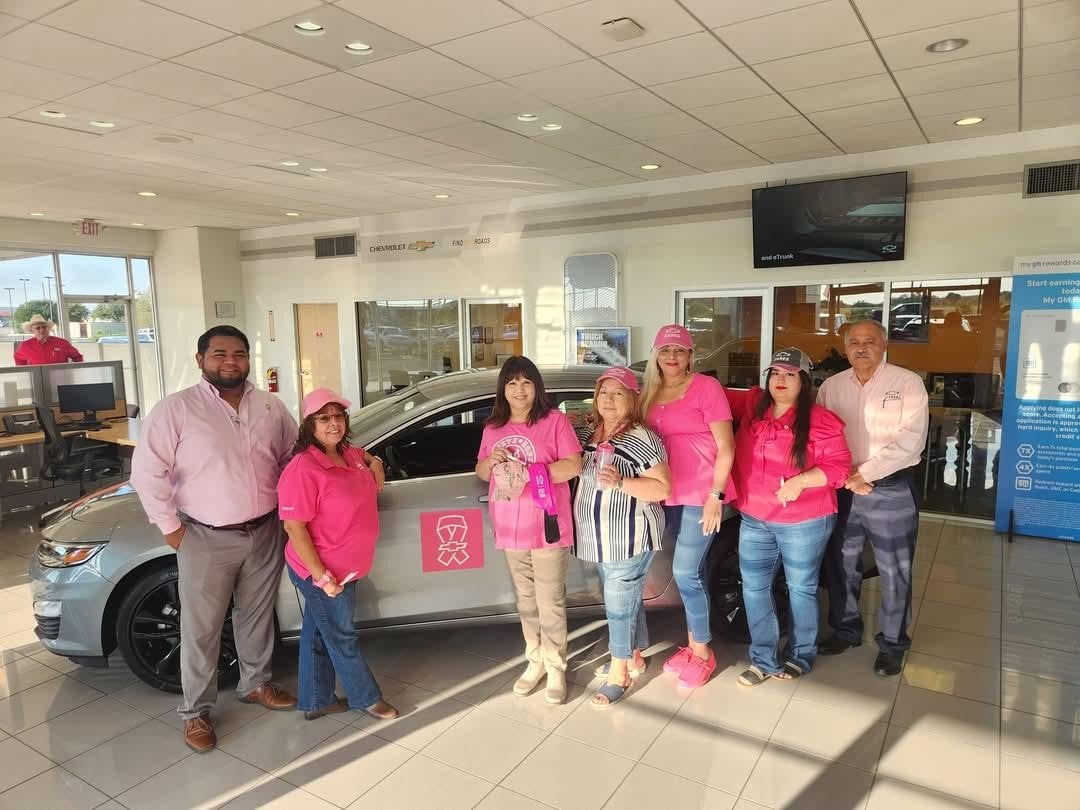 Team in pink posing with decorated car for breast cancer awareness